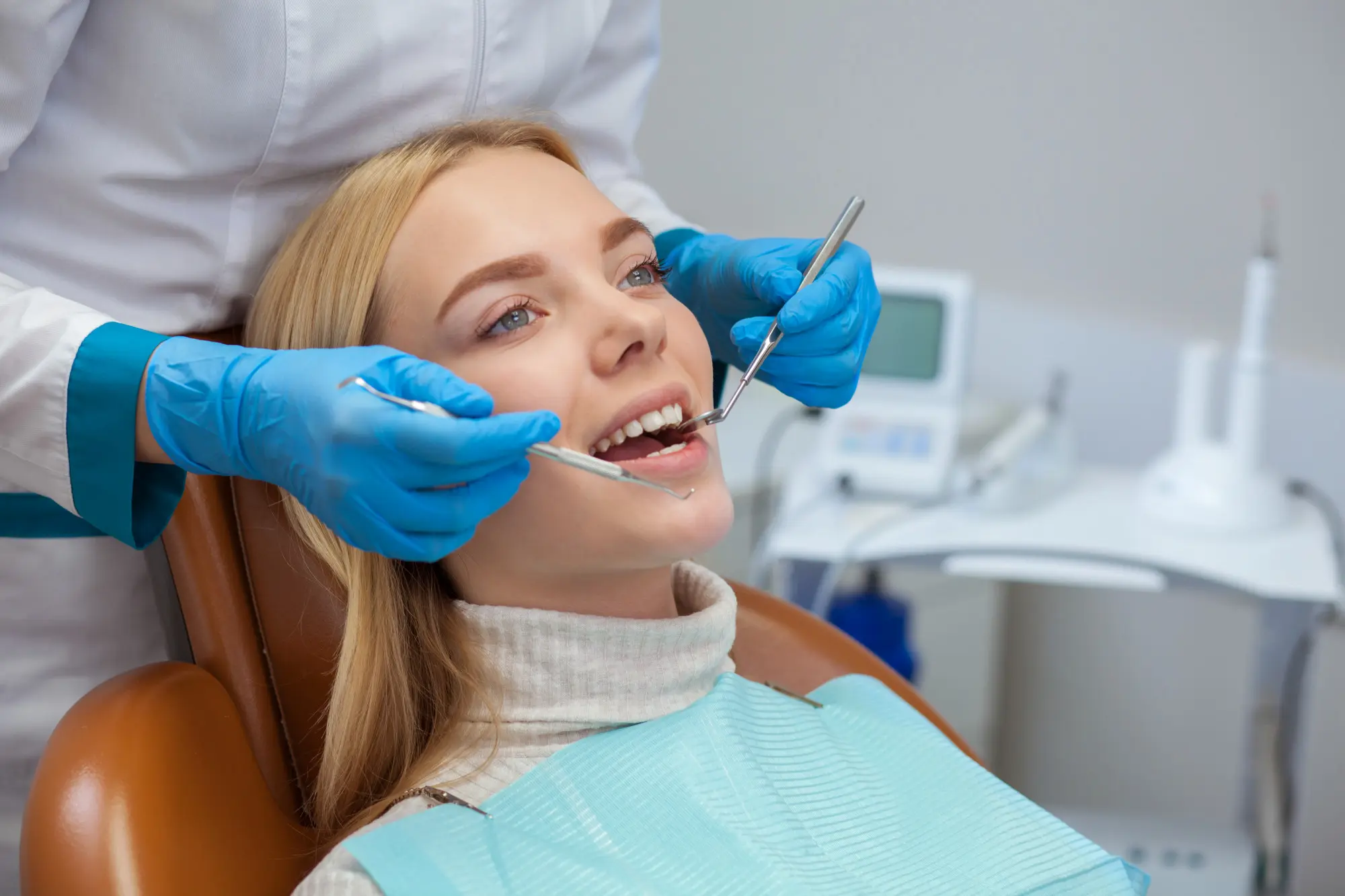 a woman sitting in a chair with a dentist holding tools